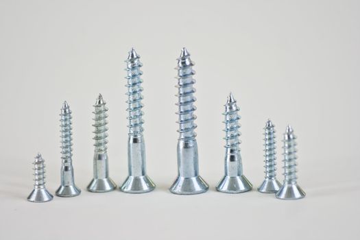 Different sizes of screws lined up in desending order on a white background.