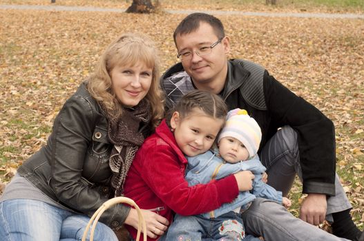 The young family in park, sits on a ground