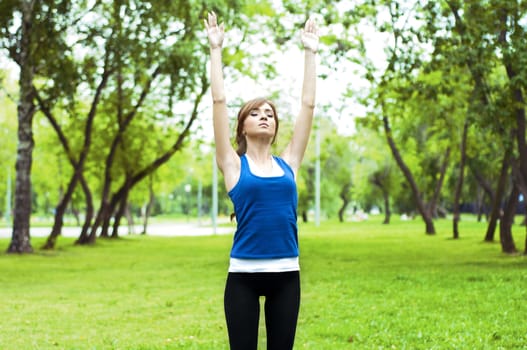 young woman is engaged in yoga, in summer forest on a green grass