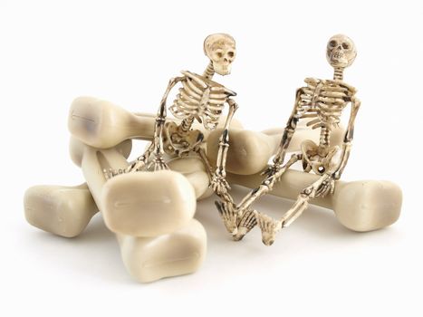 Two skeleton figures sitting on some bones isolated on a white background