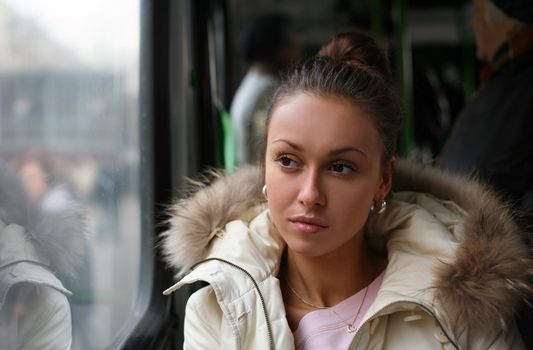 The sad beautiful girl looks in a window of the bus