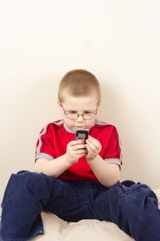 the small boy in glasses uses mobile phone