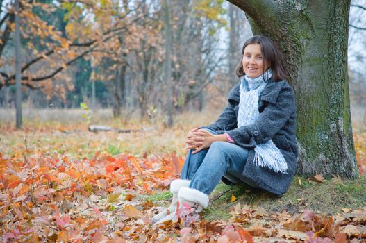 Cute happy young woman sitting in the autumn park.