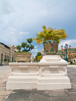 Bonzai and golden cane palm place in painted pottery pots on modern base in front of Grand Palace, Bangkok, Thailand