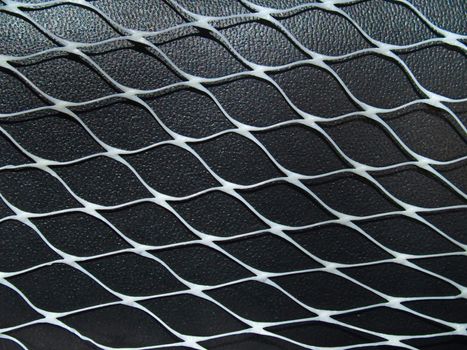 Closeup white net on black leather surface