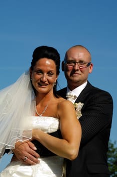 Happy wedding couple togeter. The groom is holding his arms around his bride.