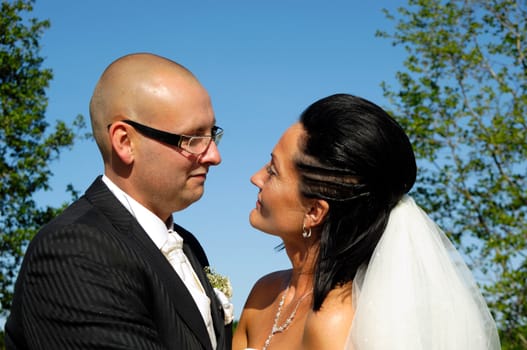 Bride and groom are standing close together looking at each other.