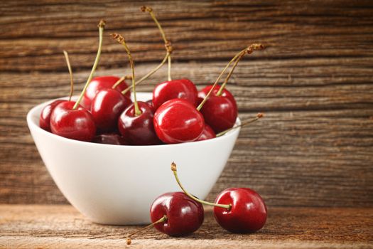 Red cherries in bowl on old barn wood