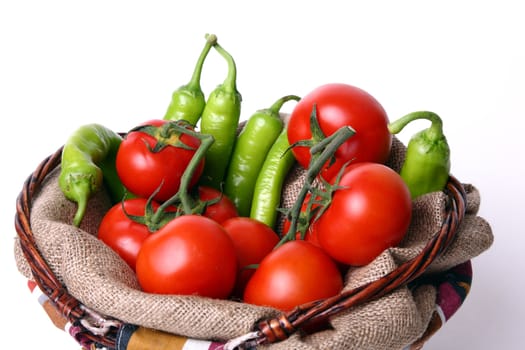 Basket with red tomatoes and geen peperoni on white background