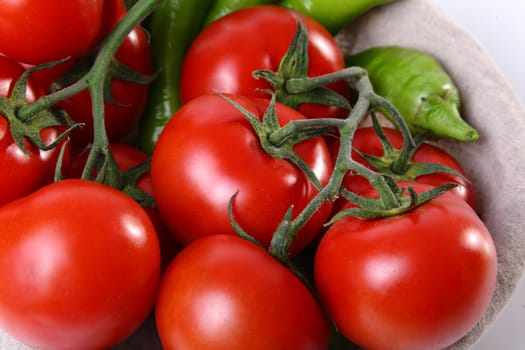 Close up of red tomatoes and green peperoni on white background