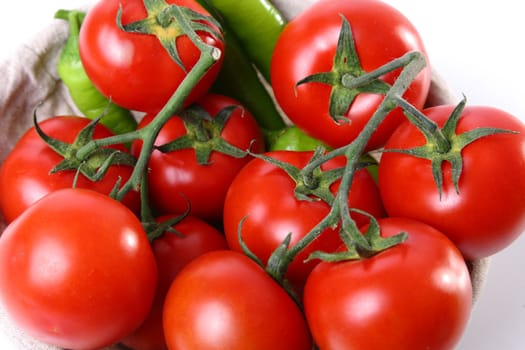 Close up of red tomatoes and green peperoni on white background