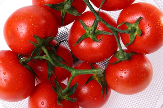 Glass basket with red tomatoes and water drops