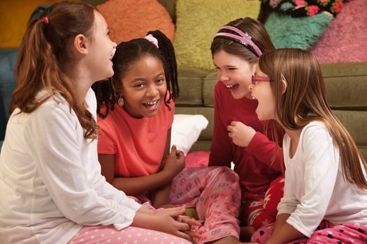 Group of four little girls in pajamas laugh at a sleepover