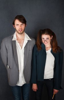 Uncomfortable nerd man and woman couple on gray background