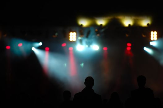 Crowd of people in front of spotlights at a concert.