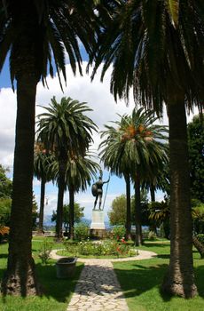 Higly decorated park of Achillion palace with Achilles monument in the background