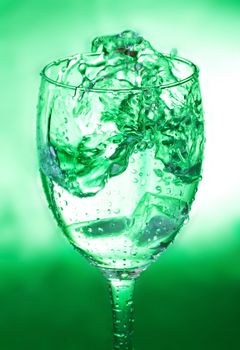 close-up glass with water splash on green background