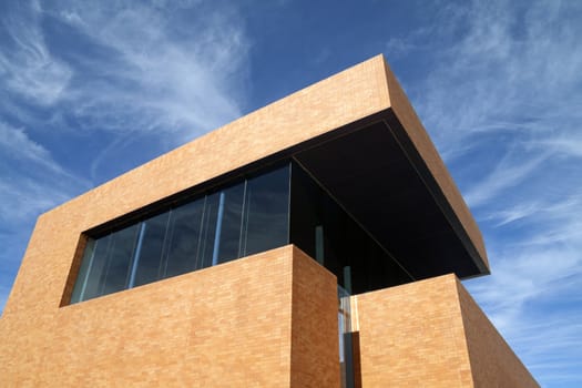 A modern brick building reaching into the blue sky 