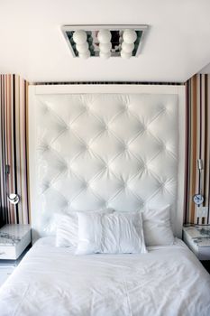 A modern white hotel bedroom with night stand