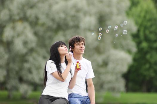 Happy young couple enjoying at park with bubbles