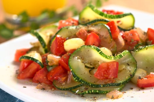 Sauteed zucchini slices, tomato cubes, onion and cooked corn grains with dried herbs and black pepper (Selective Focus, Focus on the front of the zucchini slice and tomato piece in the front)