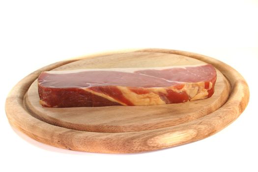smoked bacon on a wooden board before a white background