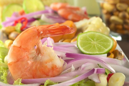 Peruvian Prawn Ceviche: King prawn on red onions and lettuce with corn grains and lime slices in the back (Selective Focus, Focus on the prawn)  