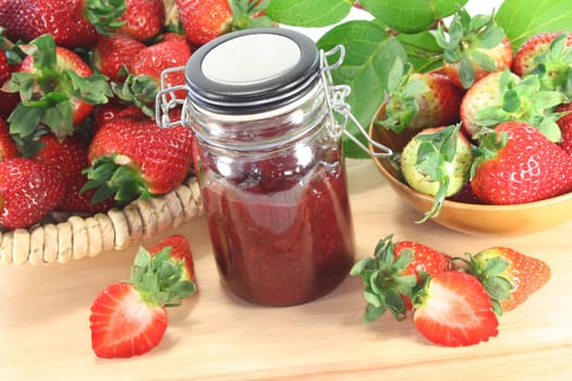 Strawberry jam with fresh strawberries on a wooden board
