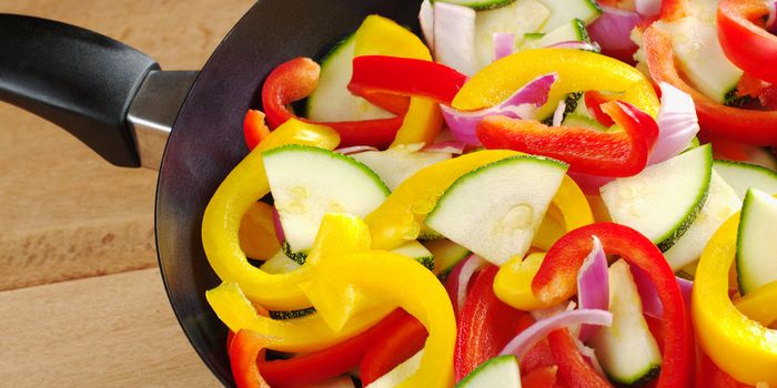 The raw ingredients of ratatouille in a frying pan. Ratatouille is a light summer French dish which mainly consists of zucchini, pepper and onions, but there are many variations to it (Selective Focus, Focus on the upper half of the image)