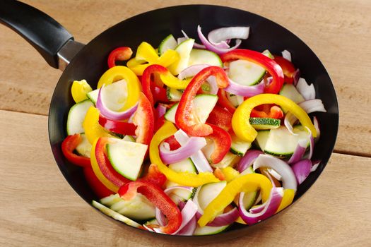 The raw ingredients of ratatouille in a frying pan. Ratatouille is a French light summer dish which mainly consists of zucchini, pepper and onions, but there are many variations to it (Selective Focus, Focus on the middle of the vegetables)