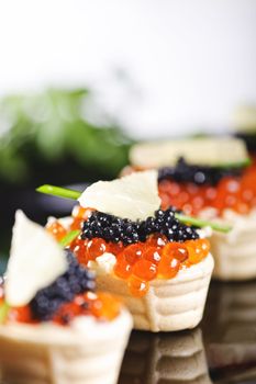 snacks with salmon roe and vegetables on a black plate