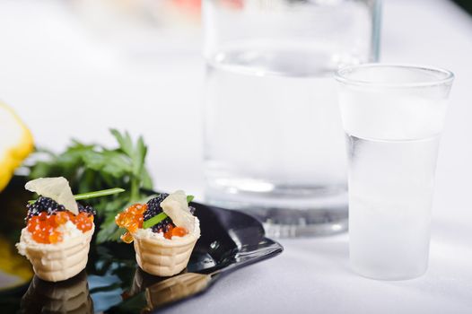 snacks with salmon roe and vegetables on a black plate