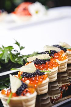 snacks with salmon roe and vegetables on a black plate
