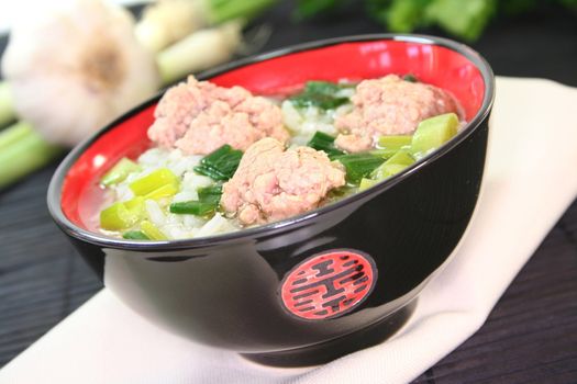 Thai rice soup with meat balls, rice and spring onions