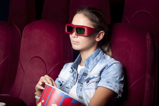 young woman sitting alone in the cinema and watching a movie