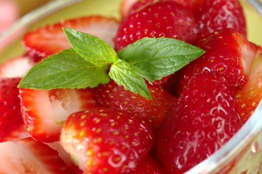Mint leaf garnishing fresh half strawberries in a glass bowl (Selective Focus, Focus on the mint leaf)