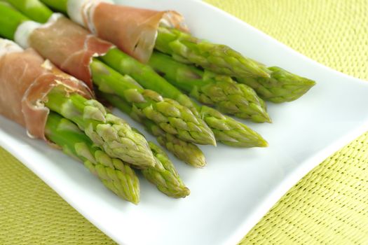 Green asparagus with ham (Selective Focus, Focus on the asparagus heads in the front)