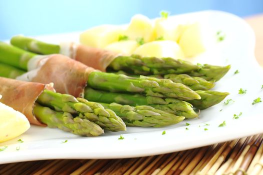 Green asparagus with ham and potatoes (Selective Focus, Focus on the asparagus heads in the front)