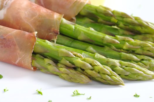 Green asparagus with ham (Selective Focus, Focus on the two asparagus heads in the front)