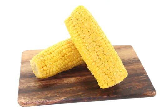 two corn on a wooden board before white background