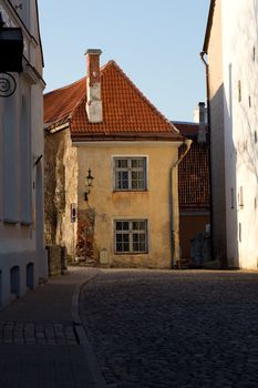 Old yellow painted house between narrow streets in Tallinn, capital of Estonia at sunset