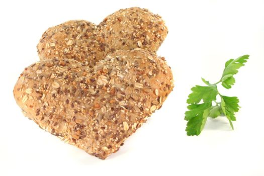 Whole grain bread into heart shape with parsley on a white background