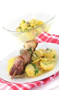 Shashlik skewer of pork with potato salad and garlic