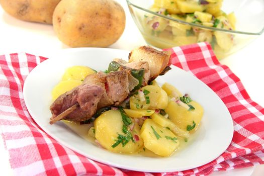 Shashlik skewer of pork with potato salad and garlic