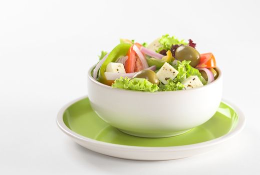 Greek salad out of white cheese, olives, red onions, tomato, bell pepper, cucumber and lettuce with herbs (Selective Focus, Focus on the cheese) 