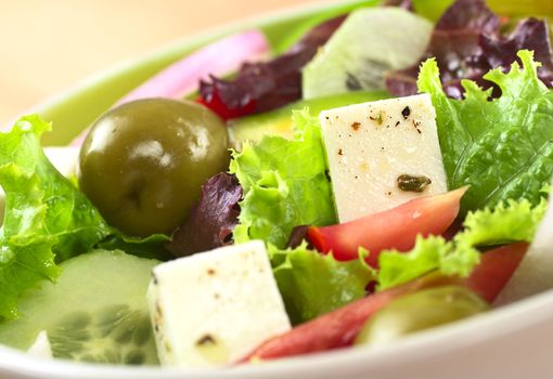 Greek salad out of cheese, green olives, tomato, green bell pepper, red onion, cucumber and lettuce (Selective Focus, Focus on the cheese on the right) 