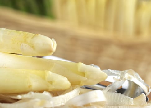 White asparagus with peels and green and white asparagus in basket in the back (Selective Focus, Focus on the longest asparagus head)