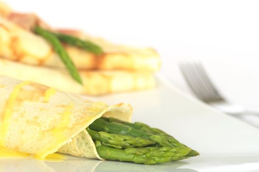 Green asparagus wrapped in crepes with Hollandaise sauce on top (Very Shallow Depth of Field, Focus on the asparagus in the front)