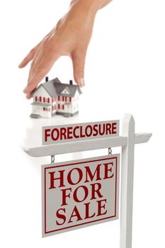 Womans Hand Choosing House with Foreclosure Home For Sale Real Estate Sign in Front Isolated on White.