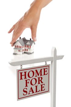 Womans Hand Choosing House with Home For Sale Real Estate Sign in Front Isolated on White.